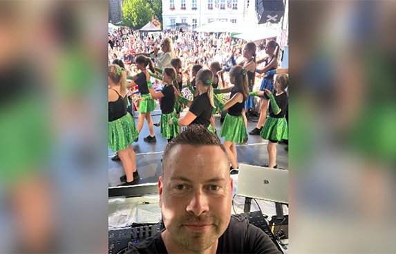 Ein Porträt von Dj Rico und im Hintergrund das Stadtfest in Pritzwalk